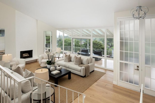 sunroom / solarium featuring lofted ceiling, a large fireplace, and a chandelier