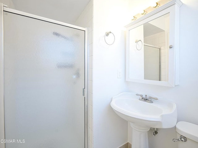 bathroom featuring a shower with door and toilet