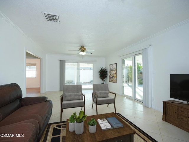 tiled living room featuring crown molding, ceiling fan, and plenty of natural light