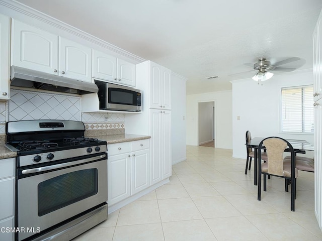 kitchen with light tile patterned flooring, appliances with stainless steel finishes, tasteful backsplash, white cabinets, and ceiling fan