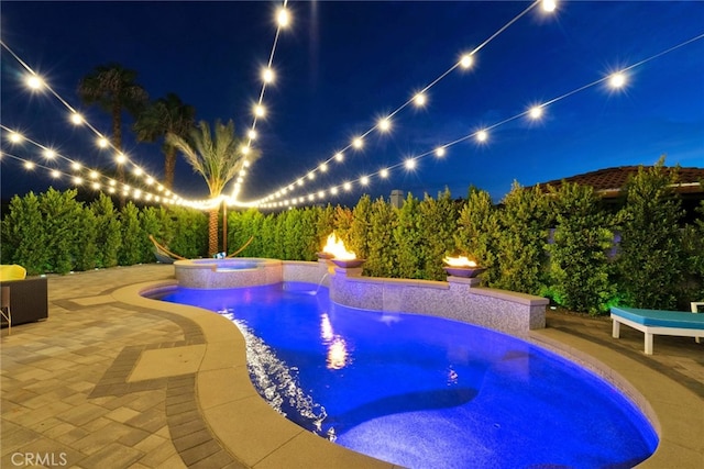 pool at twilight featuring a patio and an in ground hot tub