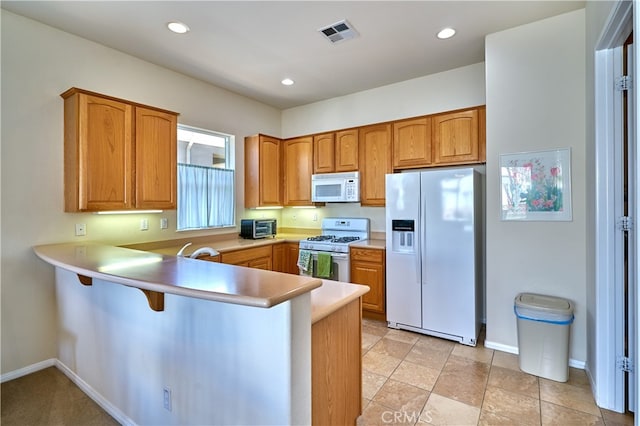 kitchen featuring white appliances, a breakfast bar area, and kitchen peninsula