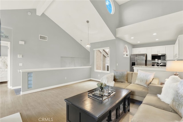 living room with high vaulted ceiling, beam ceiling, and light hardwood / wood-style flooring