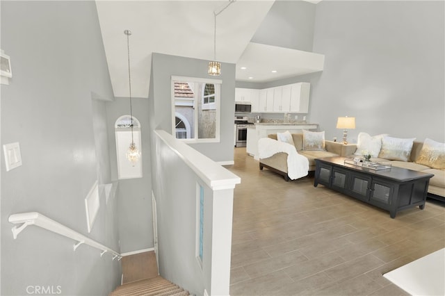 living room with a chandelier, light hardwood / wood-style flooring, and a high ceiling