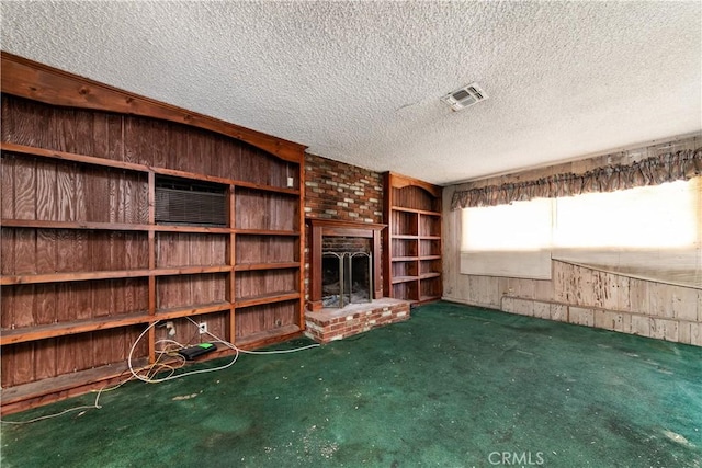 unfurnished living room featuring wooden walls, a fireplace, a textured ceiling, and dark colored carpet