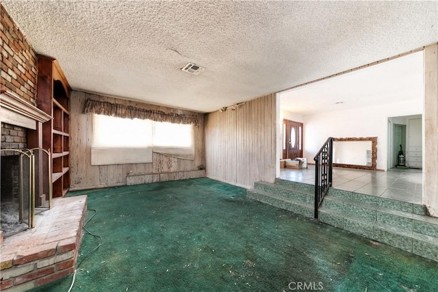 unfurnished living room with a fireplace, a textured ceiling, and carpet