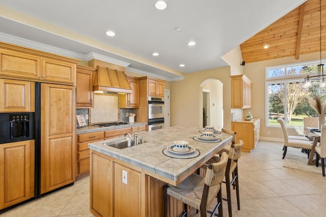 kitchen with an island with sink, stainless steel appliances, sink, and light tile patterned floors