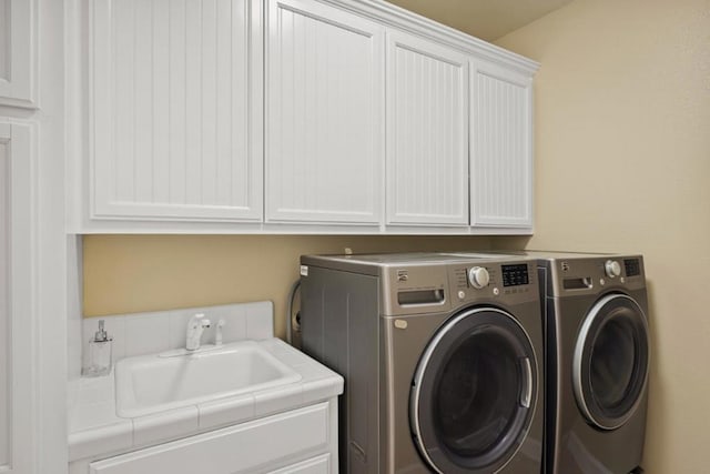 laundry area featuring sink, washing machine and dryer, and cabinets