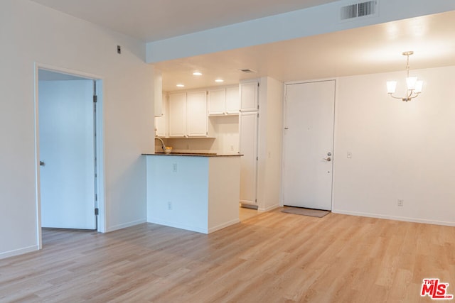 kitchen with pendant lighting, light hardwood / wood-style flooring, a chandelier, and white cabinets