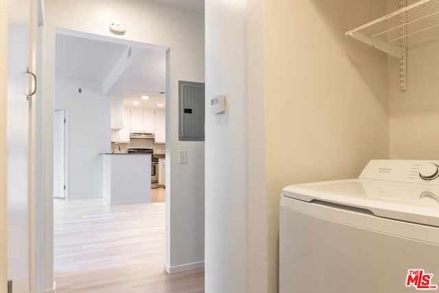 washroom with washer / dryer, electric panel, and light wood-type flooring