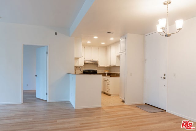 kitchen featuring sink, light wood-type flooring, white cabinets, pendant lighting, and stove