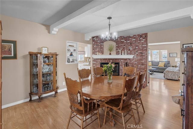 dining room with a fireplace, light hardwood / wood-style floors, beam ceiling, and a notable chandelier