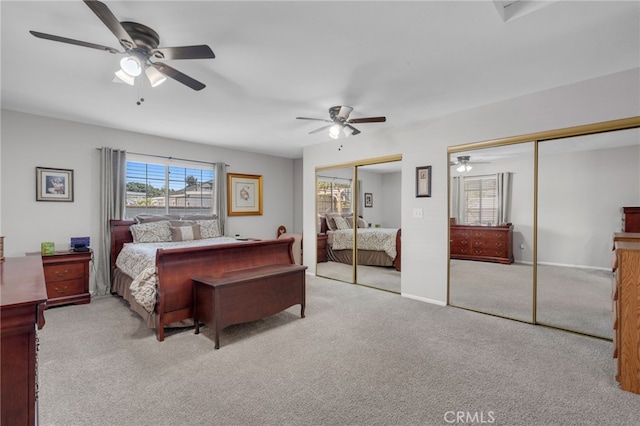 bedroom with two closets, light colored carpet, and ceiling fan