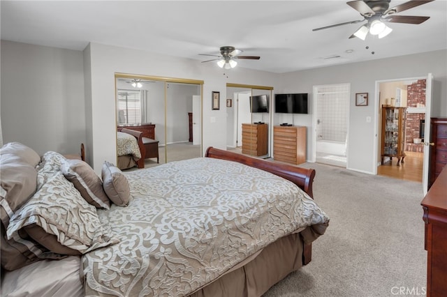 bedroom with multiple closets, light colored carpet, ensuite bathroom, and ceiling fan