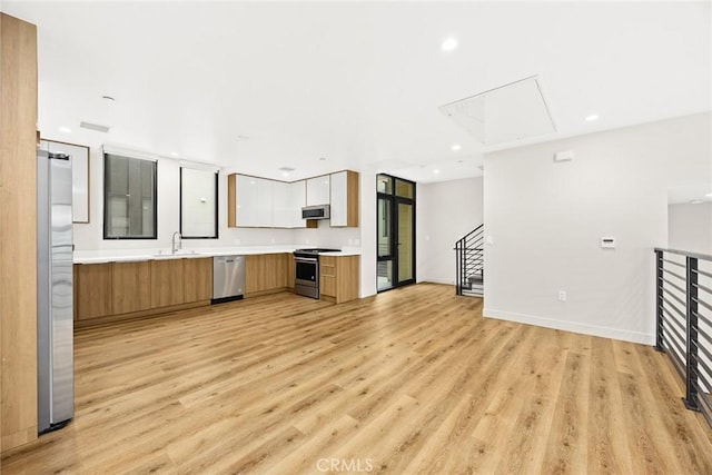 kitchen featuring sink, stainless steel appliances, white cabinets, and light wood-type flooring