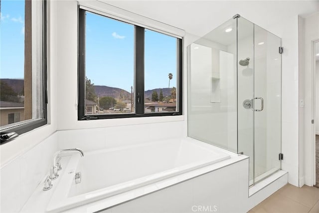 bathroom featuring independent shower and bath, a mountain view, and tile patterned floors