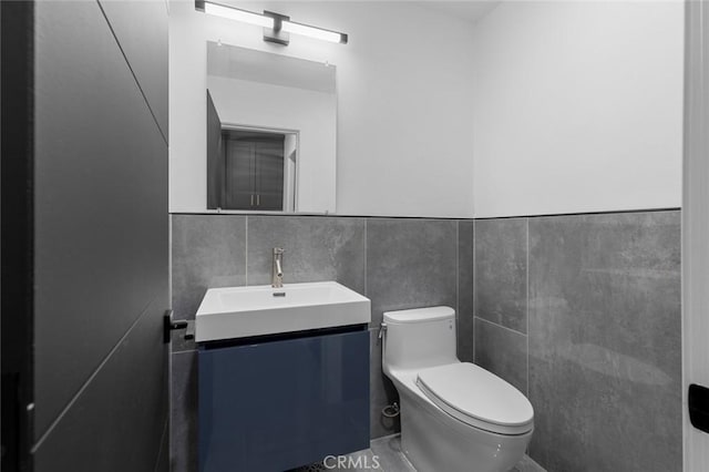 bathroom with vanity, toilet, and tile walls