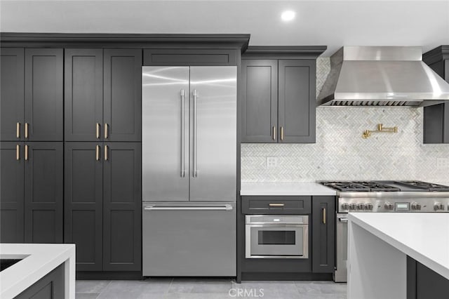 kitchen with tasteful backsplash, wall chimney range hood, and premium appliances