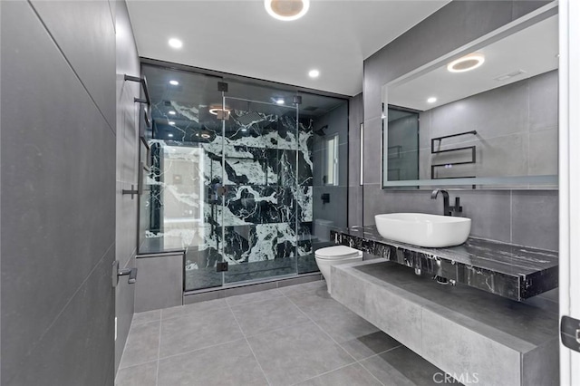 bathroom featuring toilet, a shower with shower door, sink, and tile walls