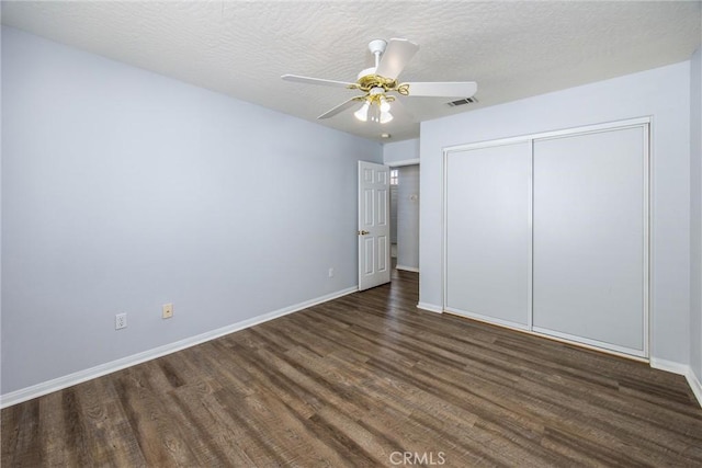 unfurnished bedroom featuring ceiling fan, dark hardwood / wood-style flooring, a closet, and a textured ceiling