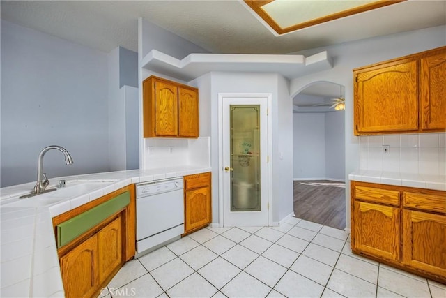 kitchen featuring dishwasher, sink, decorative backsplash, tile counters, and light tile patterned floors