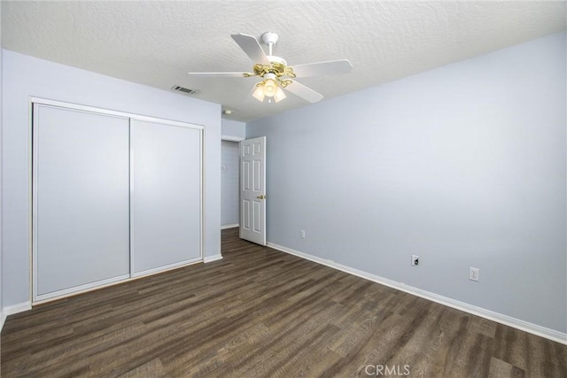 unfurnished bedroom featuring ceiling fan, dark hardwood / wood-style floors, a textured ceiling, and a closet