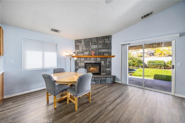 dining area with vaulted ceiling, dark hardwood / wood-style floors, and a fireplace