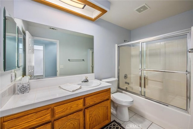 full bathroom with vanity, tile patterned floors, shower / bath combination with glass door, and toilet