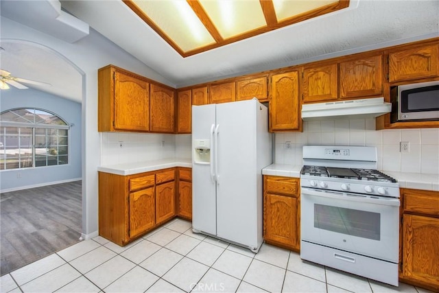 kitchen with white appliances, vaulted ceiling, light tile patterned floors, ceiling fan, and backsplash