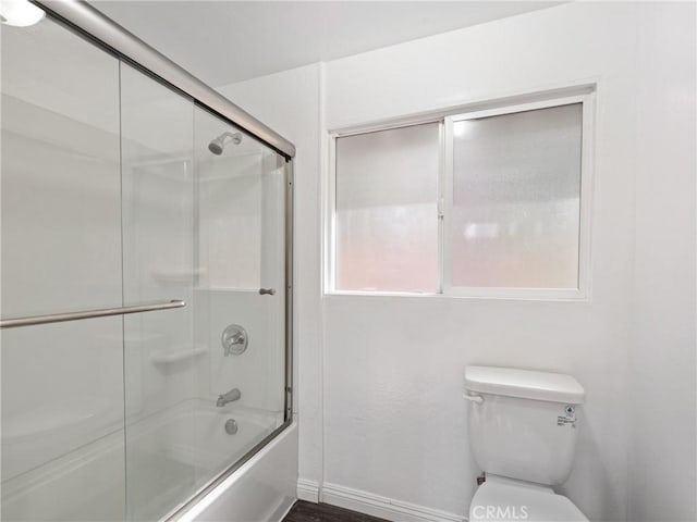 bathroom with shower / bath combination with glass door and toilet