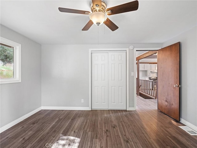 unfurnished bedroom with dark wood-type flooring, ceiling fan, and a closet