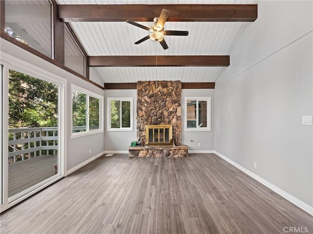 unfurnished living room featuring beamed ceiling, a stone fireplace, and hardwood / wood-style floors