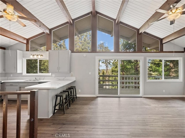 kitchen featuring dark hardwood / wood-style flooring, a breakfast bar area, ceiling fan, and kitchen peninsula