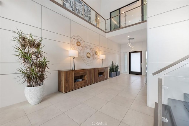 foyer entrance featuring a towering ceiling, tile walls, and tile patterned floors