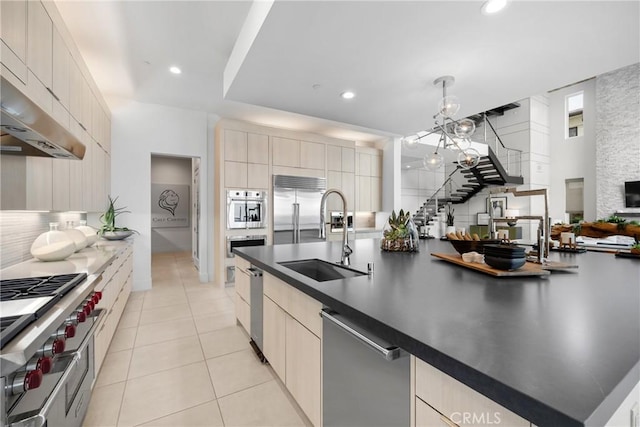 kitchen with light tile patterned flooring, sink, premium appliances, pendant lighting, and decorative backsplash