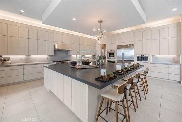 kitchen featuring hanging light fixtures, stainless steel appliances, a spacious island, and light tile patterned flooring