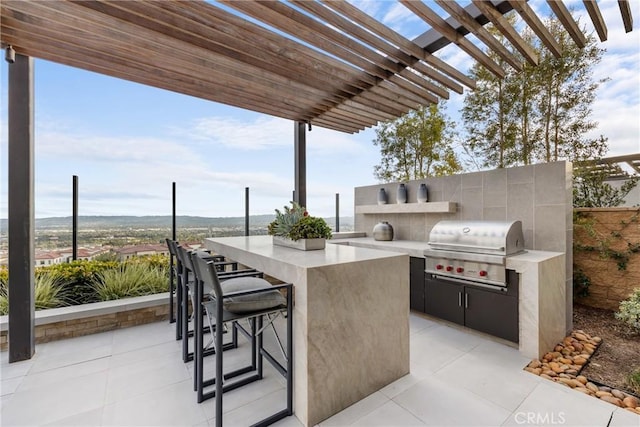 view of patio with a bar, a grill, a pergola, and exterior kitchen