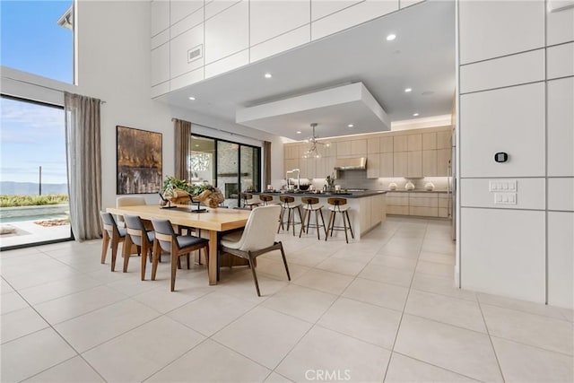 dining space with a towering ceiling, a chandelier, and light tile patterned floors