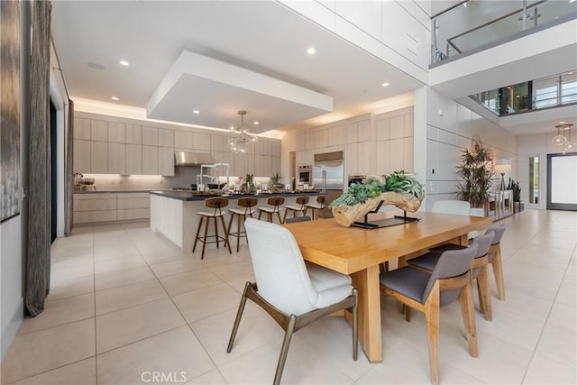 tiled dining area featuring a towering ceiling and a chandelier