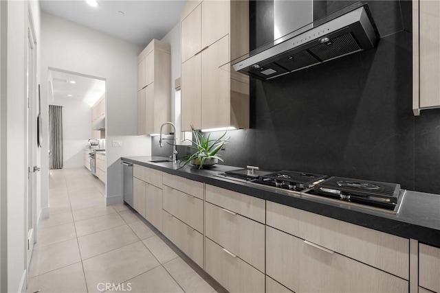 kitchen with light tile patterned flooring, stainless steel dishwasher, sink, and wall chimney range hood