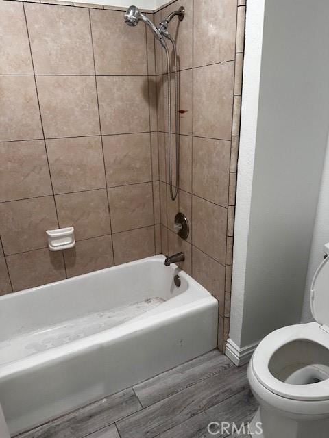 bathroom featuring wood-type flooring, toilet, and tiled shower / bath