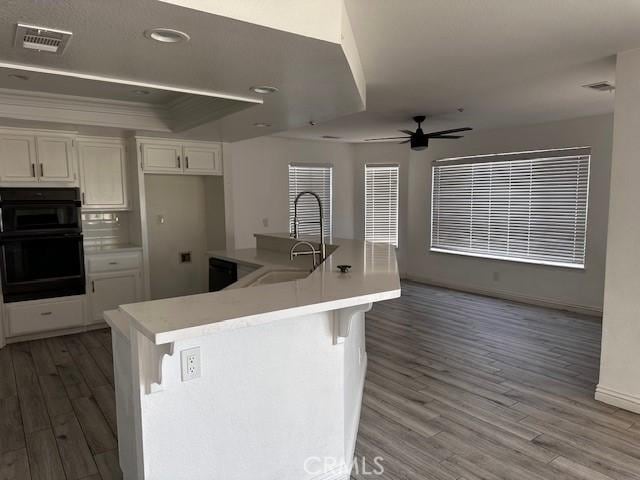 kitchen with an island with sink, sink, white cabinets, and a breakfast bar