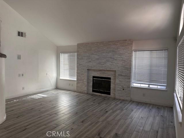 unfurnished living room with a large fireplace, dark hardwood / wood-style flooring, and high vaulted ceiling