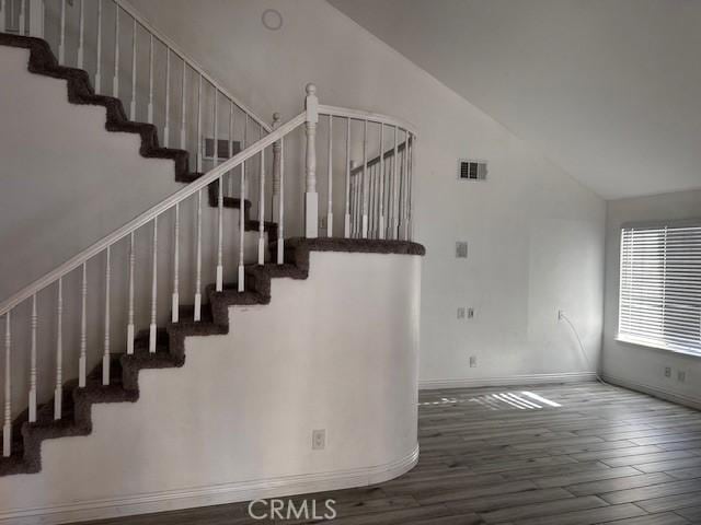 staircase with hardwood / wood-style flooring and high vaulted ceiling