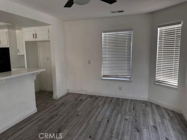 kitchen with dark wood-type flooring, ceiling fan, double oven, and white cabinets