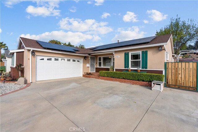 ranch-style home with a garage and solar panels