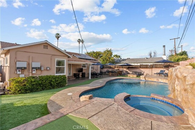 view of pool featuring an in ground hot tub, a yard, and a patio area