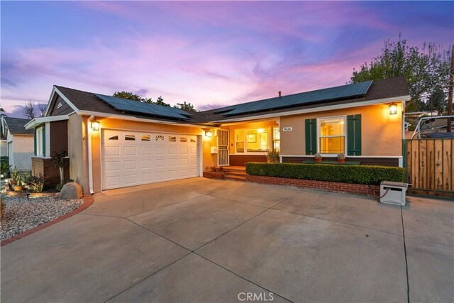 ranch-style home featuring a garage and solar panels