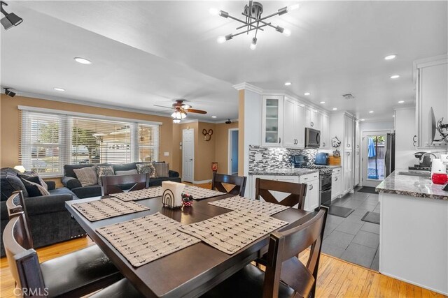 dining area with crown molding, ceiling fan with notable chandelier, light hardwood / wood-style floors, and sink