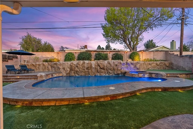 pool at dusk featuring a yard and an in ground hot tub